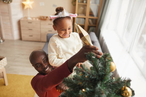 istock Little Girl Putting Star on Christmas Tree 1286136397