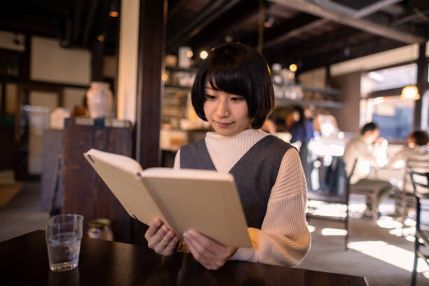 istock Young woman reading book in old Japanese restaurant 1286140607