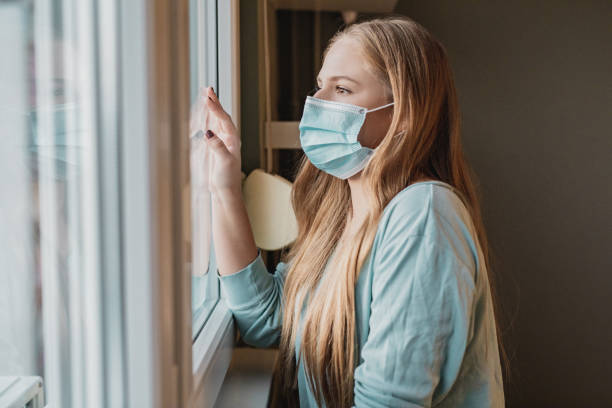 istock Young woman with face mask by the window 1286142210
