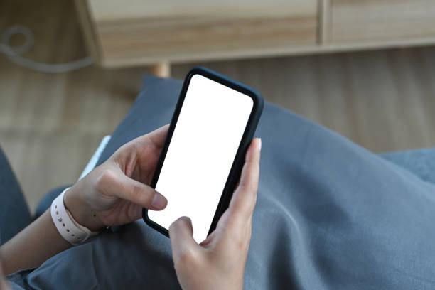 istock Close up view of female freelancer hands using smartphone mockup while sitting on couch. Blank screen mobile phone for graphic display montage. 1286143068