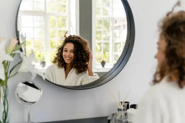 Photo of Young adult afro american woman in bathrobe at bathroom