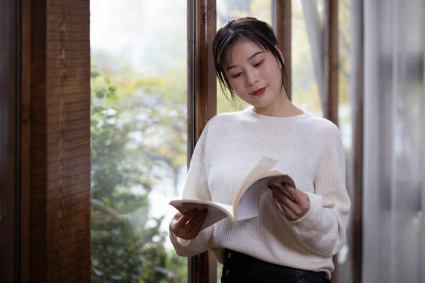 istock Asian girl reading by the window 1286144992