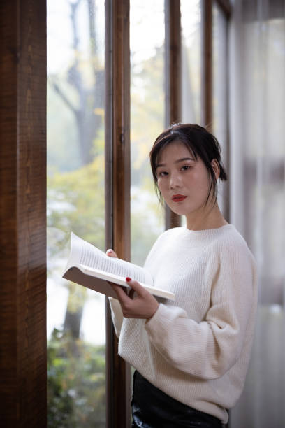 istock Asian girl reading by the window 1286145007
