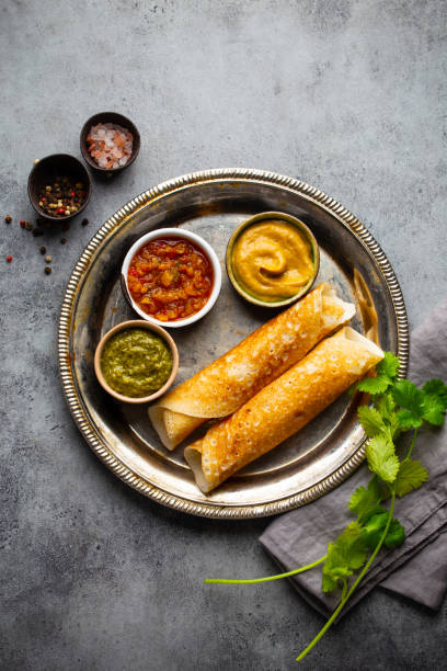 traditional indian rice pancakes dosa with different dips chutney and seasonings on rustic metal plate on stone background table. quick meal or vegetarian snack of south india, top view - cooked vertical high angle view lentil imagens e fotografias de stock