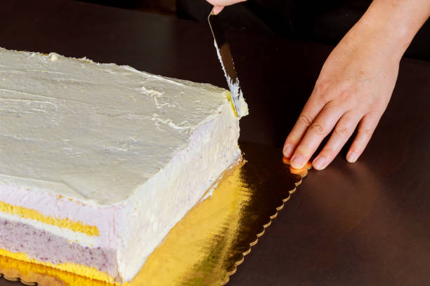 istock Chef cover with icing festive cake. Making layer sponge cake. 1286147438