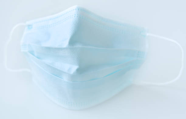 istock Surgical mask with rubber ear straps. Protective mask from bacteria and virus infection. Coronavirus and flu virus protection concept. 1286150174