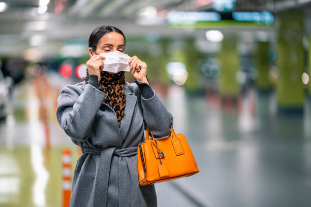 istock Casually dressed woman putting on a protective face mask in the garage 1286150423