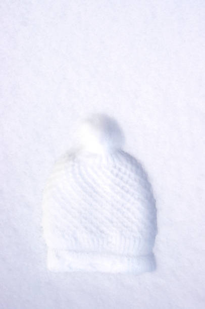 imprint of knit hat with pompom in white snow with copy space
