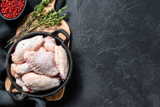 istock Marinated chicken wings with spices and herbs in a pan. Black background. Top view. Copy space 1286151680