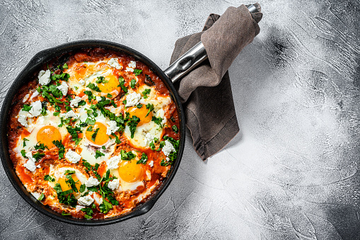 Breakfast with Fried eggs, tomatoes. Shakshuka in pan. Turkish  traditional dishes. Gray background. Top view. Copy space.