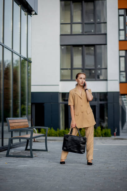 istock Young female executive standing outside office building talking on cell phone. Caucacian businesswoman making a phone call while standing against a corporate office building 1286155135