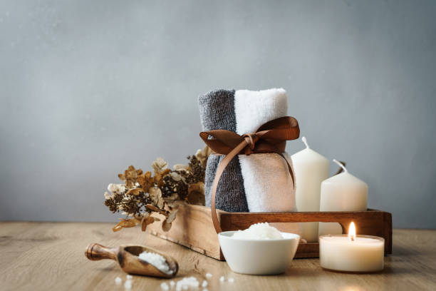 Two rolled up towels and wellness items on a rustic wood table