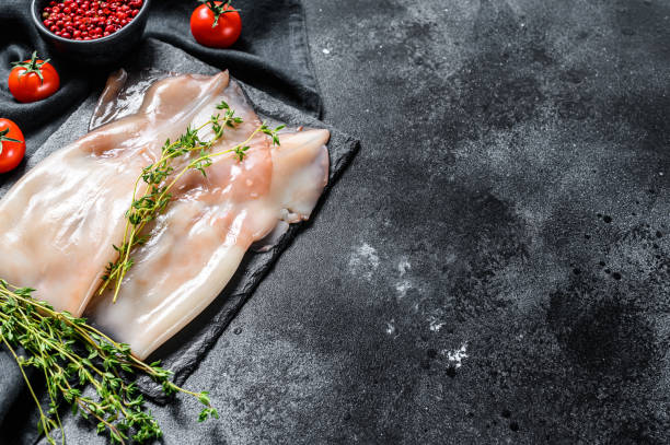 istock Fresh raw whole squid. Black background. Top view. Copy space 1286157874