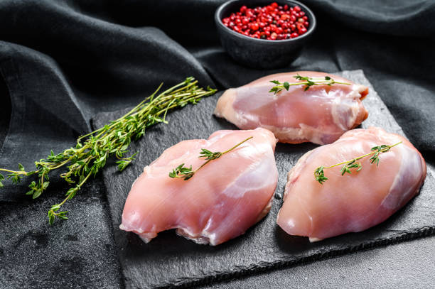 istock Chicken thigh fillet without skin. Black background. Top view 1286158230