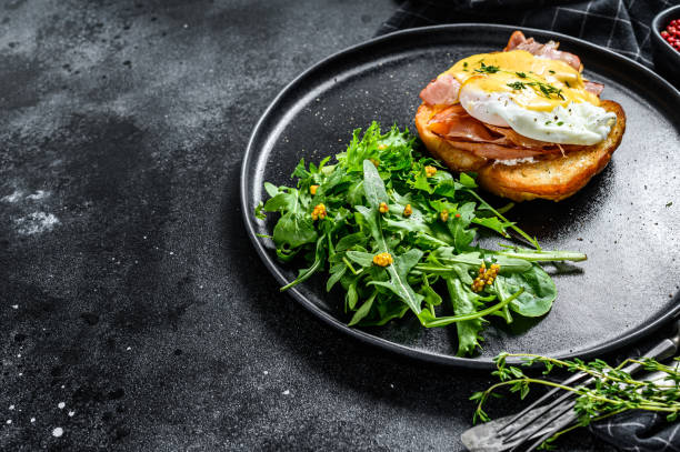istock Breakfast Burger with bacon, egg Benedict, hollandaise sauce on brioche bun. Black background. Top view. Copy space 1286158436