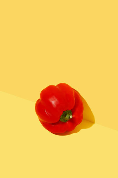 pimentão fresco vermelho em fundo amarelo ousado - green bell pepper bell pepper red bell pepper groceries - fotografias e filmes do acervo