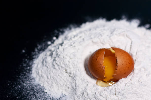 istock A broken chicken egg on a stack of white flour in the lower right corner. 1286161736