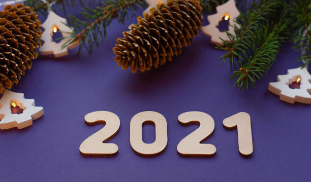 istock Christmas tree natural branches with a glitters and the number 2021 on a purple background. Bull - symbol of the new year 2021. 1286162004