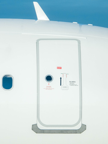 A closed door at the side of a large airline aircraft. The door secured to prevent unwanted pests or passengers from getting on board.