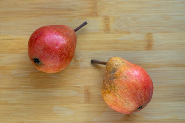 deux poires fruits comestibles, savoureux fruits jaunes rouges mûris sur fond en bois - bartlett pear red pear two objects photos et images de collection