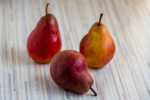 Three pears edible fruits, tasty ripened red yellow fruit on wooden background Three pears edible fruits, tasty ripened red yellow fruit still life on wooden background bartlett pear stock pictures, royalty-free photos & images