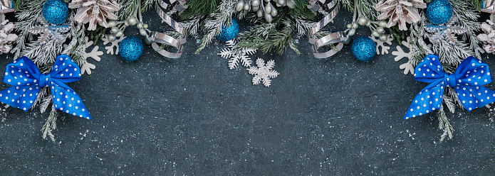 Flat lay winter header: spruce twigs in the snow with cristmas decoration in blue, silver, white colors