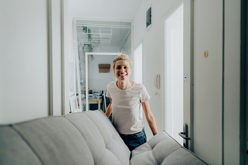 Photo of a cheerful young woman moving into a new apartment and taking in the furniture