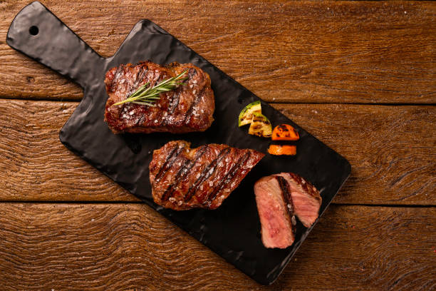 istock Grilled sliced beef steak on a black cutting board on the wooden table 1286170743