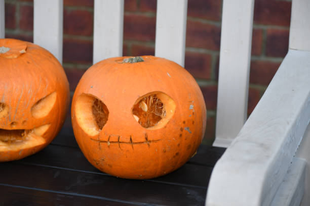 istock Two carved Halloween pumpkins on an outside bench 1286171111