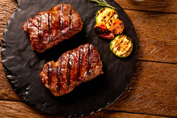 istock Grilled sliced beef steak on cutting board on black board over wooden table. 1286171236