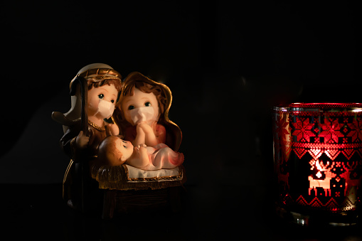 Paisaje de Navidad con delicadas figuras en la nueva normalidad del coronavirus o covid-19. José y María con chinstrap sobre fondo negro. photo