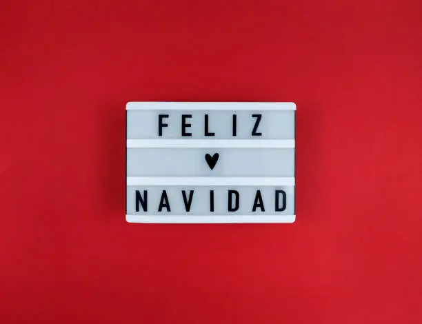 Light box with Feliz Navidad phrase, Spanish Merry Christmas on red background.
