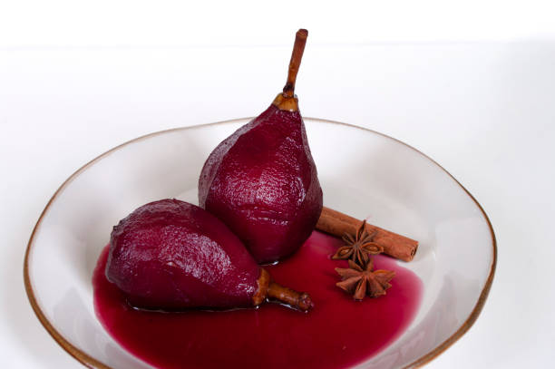 Fresh pears poached in red wine with cinnamon on white plate, Italian kitchen. Glazed fruit.