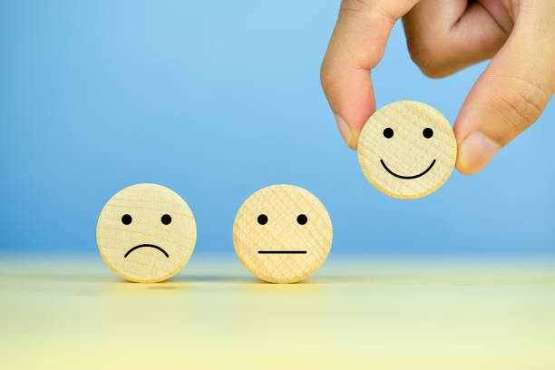 istock Customer service evaluation and satisfaction survey concepts. The client's hand picked the happy face smile face icon on wooden cube on table, blue background 1286178835