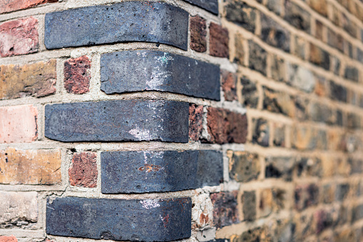 Close-up of damaged corner bricks on an old building in London, England.