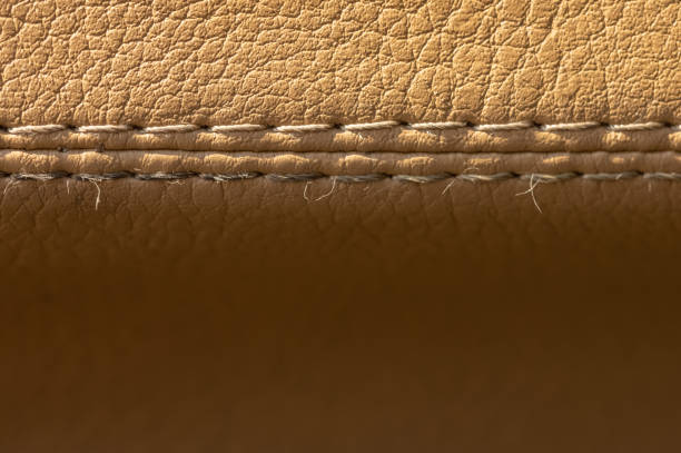 istock Beige color old leather car upholstery with stitching close-up macro. Textile auto background 1286182302