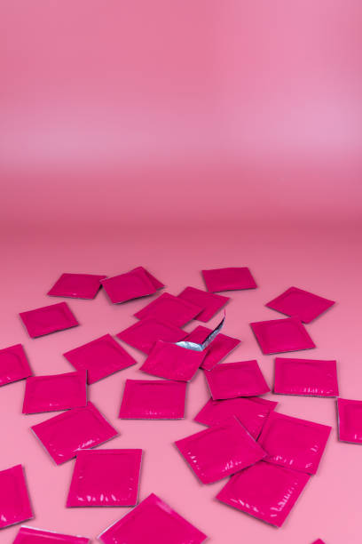 분홍색 콘돔과 밝은 분홍색 배경에 하나의 오픈 콘돔 패킷의 많은. 안전한 섹스, 관계, 사랑. 발렌타인 데이 컨셉 - condom sex education contraceptive aids 뉴스 사진 이미지