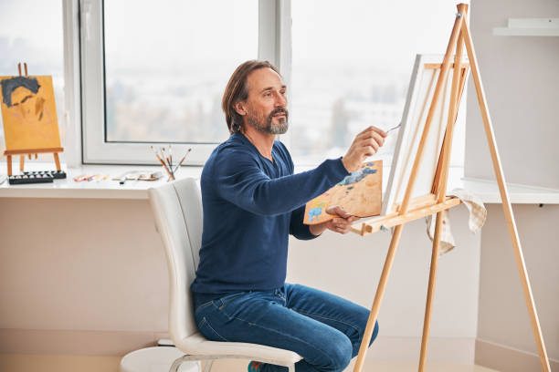 istock Creative gentleman carefully adding more colours to canvas 1286183671