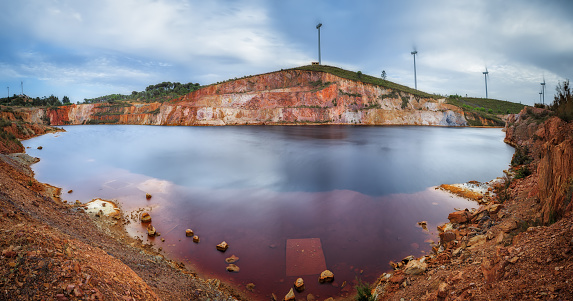 open mine flooded with water with windmills above the cliff