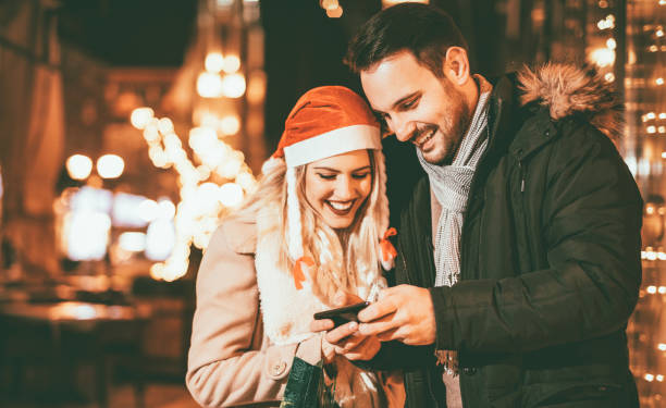 istock Young Couple Using Cell Phone In Christmas Night 1286186203