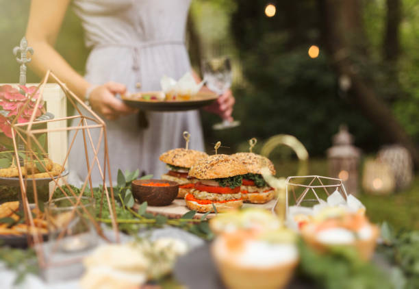 Anonymous female guests at a relaxed party in forest garden Self service food buffet. Finger food garden party stock pictures, royalty-free photos & images