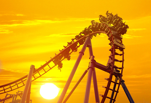 Low-angle wide shot of an inverted rollercoaster as the train goes over a loop against the sky