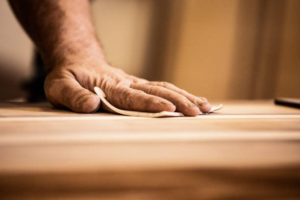 mano de un carpintero maduro frotando madera con papel de arena - final touch fotografías e imágenes de stock