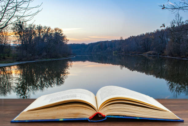 istock An expanded book. In the background, a beautiful lake at sunset 1286190925