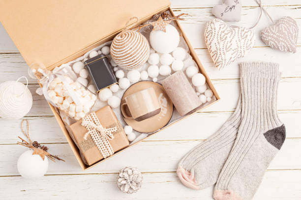 istock Preparing care package, seasonal gift box with tea, candle, cup and woolen socks. Personalized eco friendly basket for family and friends 1286194000