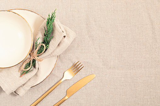Christmas festive menu mockup scene. Empty plate and fir tree branches on linen table cloth in natural neutral colors. Holiday background. Flat lay, top view