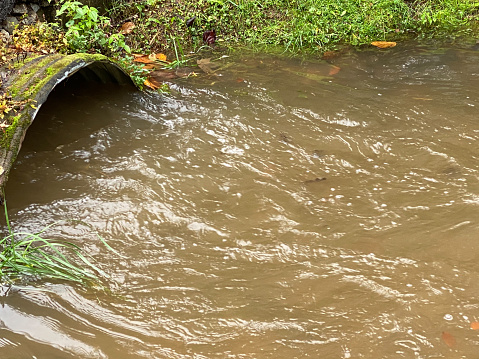Water flowing through a large storm drain after rainfall caused extreme flooding.