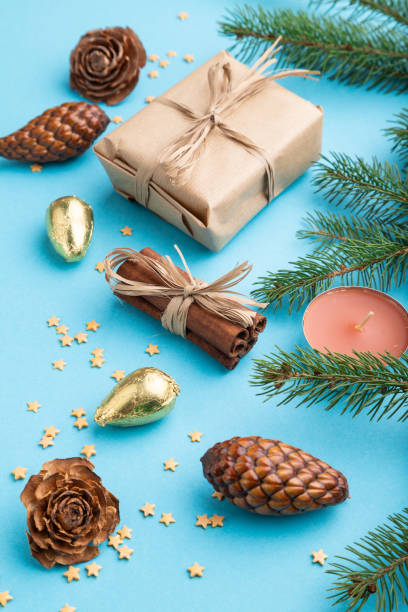 istock Christmas or New Year composition. Decorations, box, cinnamon, cones, fir and spruce branches, on a blue paper background. Side view, close up. 1286202543