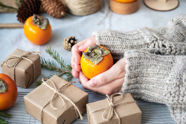 istock Natural Christmas background, craft gift boxes, cones, Christmas tree on the table, close-up, retro style. A girl in a sweater is packing gifts. The happy atmosphere of the holiday 1286203606