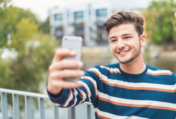 istock Cheerful young man smiling and taking selfies while enjoying 1286204103